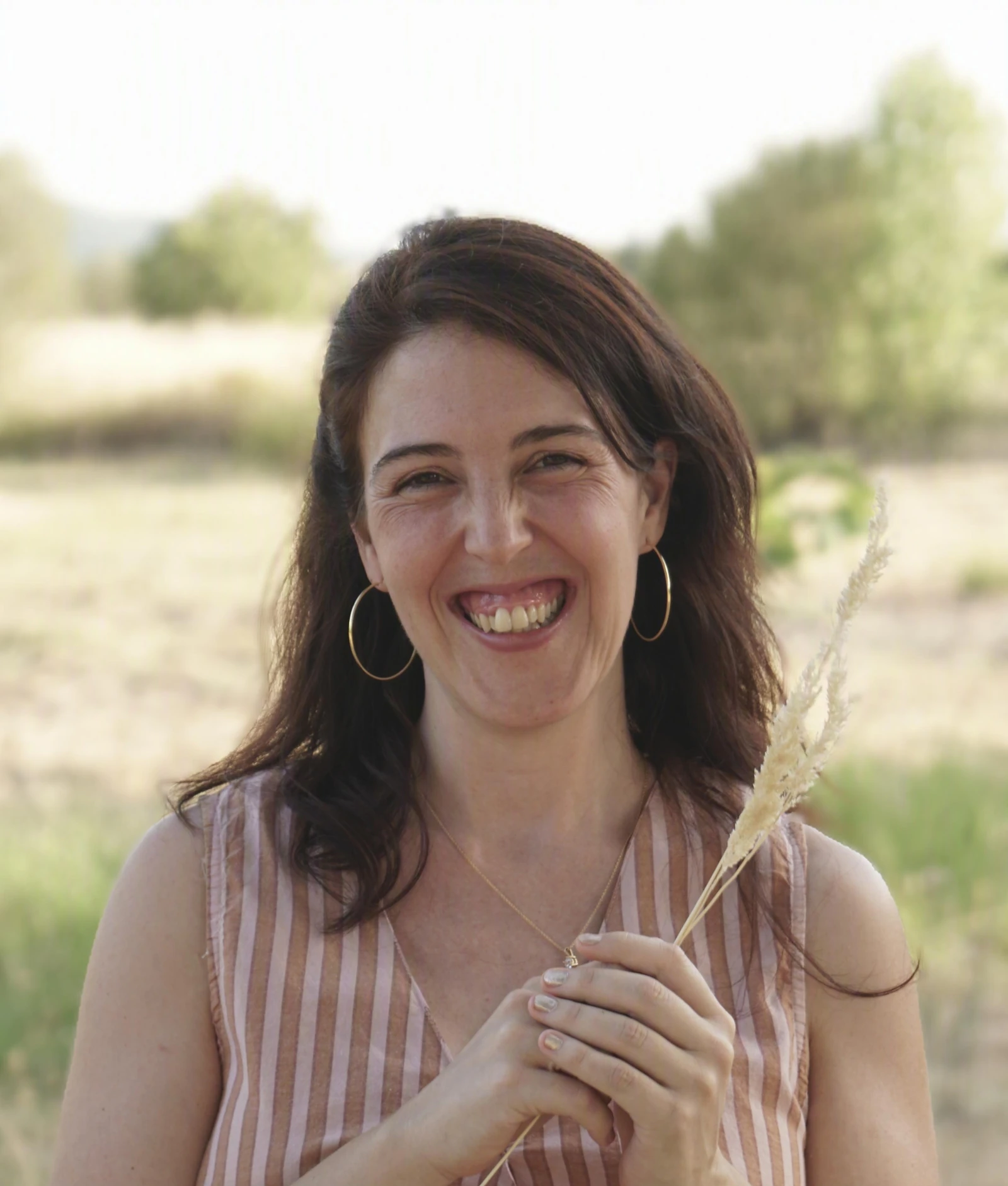 Tatiana Rivas riendo mientras sostiene una espiga de trigo