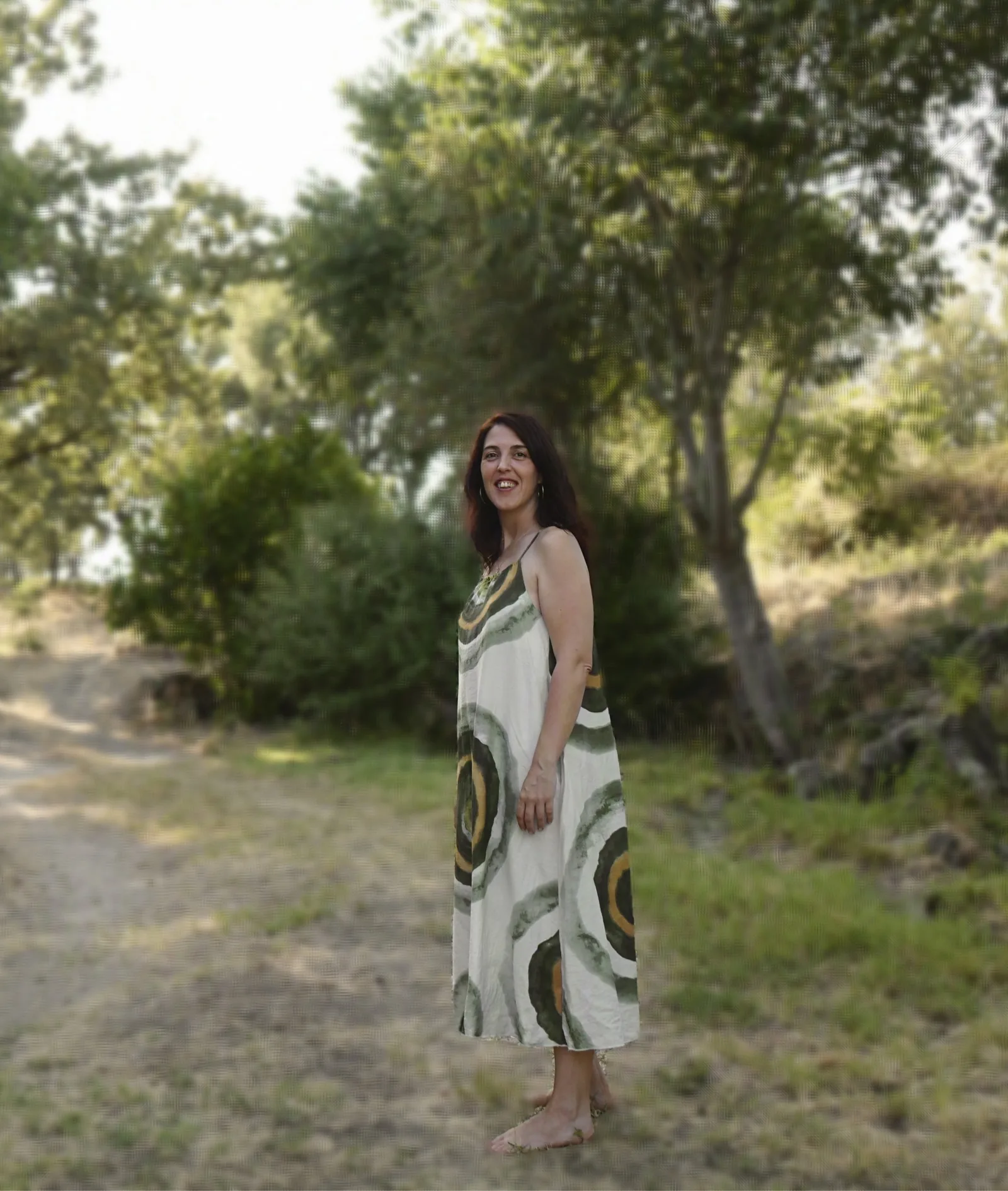 Tatiana Rivas de pie en un olivar al atardecer, en actitud de bienvenida